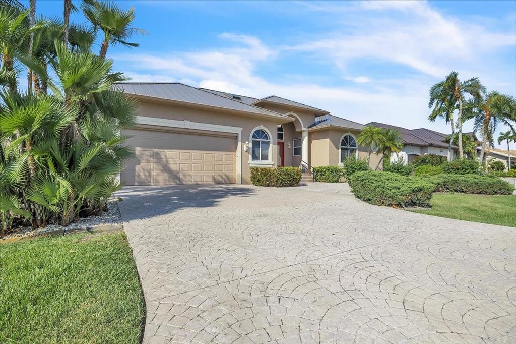 A tan single-story house with a metal roof, arched windows, and a patterned concrete driveway — 3651 ARUBA COURT, PUNTA GORDA, FL