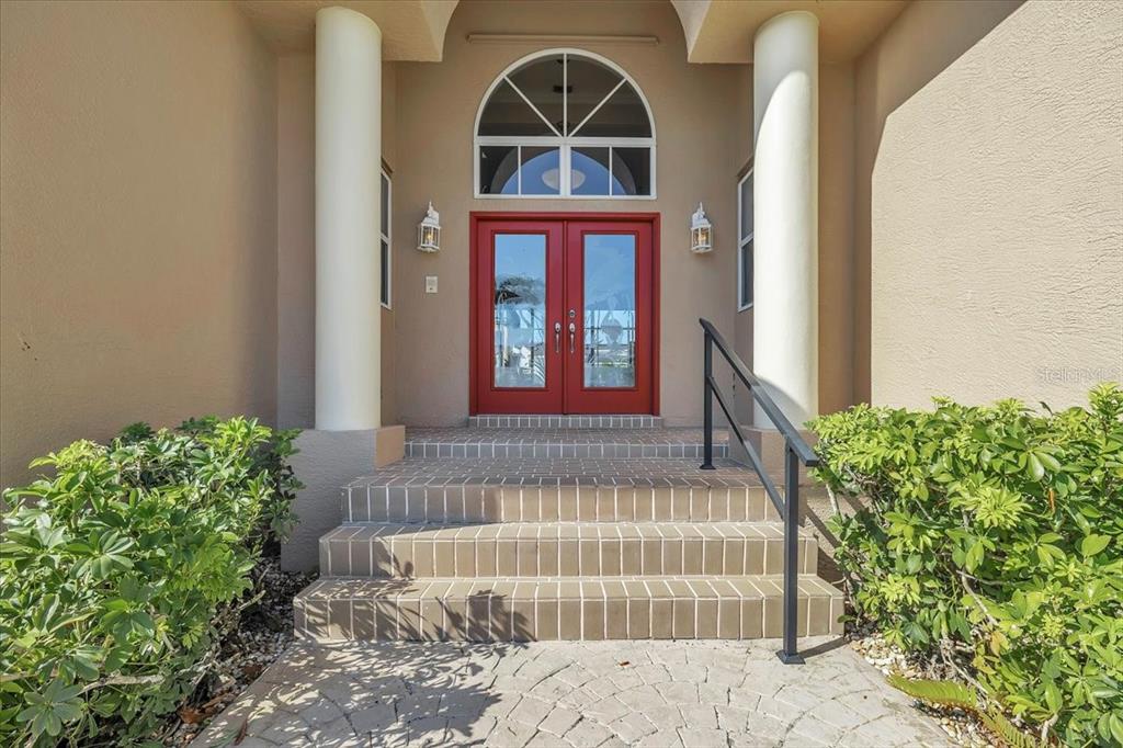 A red double front door sits at the top of brick steps under two columns — 3651 ARUBA COURT, PUNTA GORDA, FL