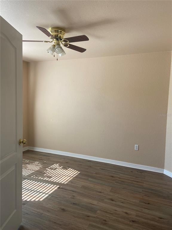 An empty bedroom features wood-look flooring, beige walls, and a ceiling fan with lights — 6775 HIGHLANDS CREEK LOOP, LAKELAND, FL