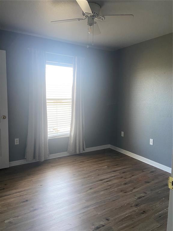 A bedroom with gray walls, wood-look flooring, a ceiling fan, and a window with curtains — 6775 HIGHLANDS CREEK LOOP, LAKELAND, FL
