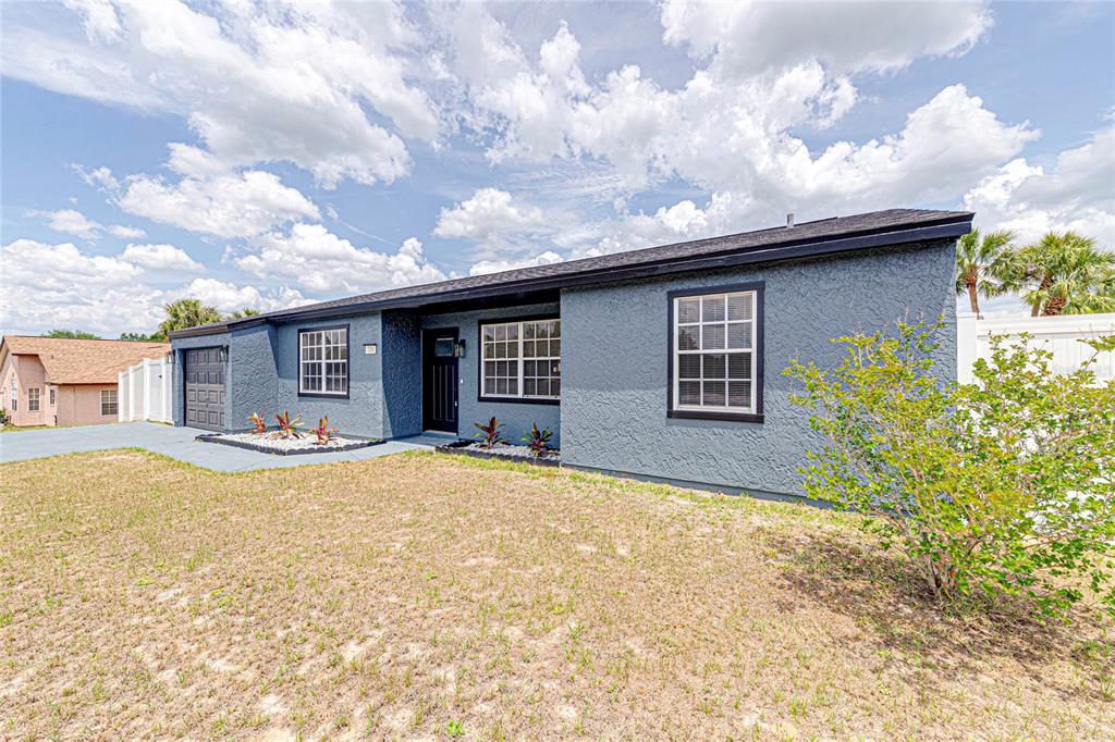 A single-story house with dark gray stucco siding, a black roof, and a front yard — 336 OAK TRACK DRIVE, OCALA, FL