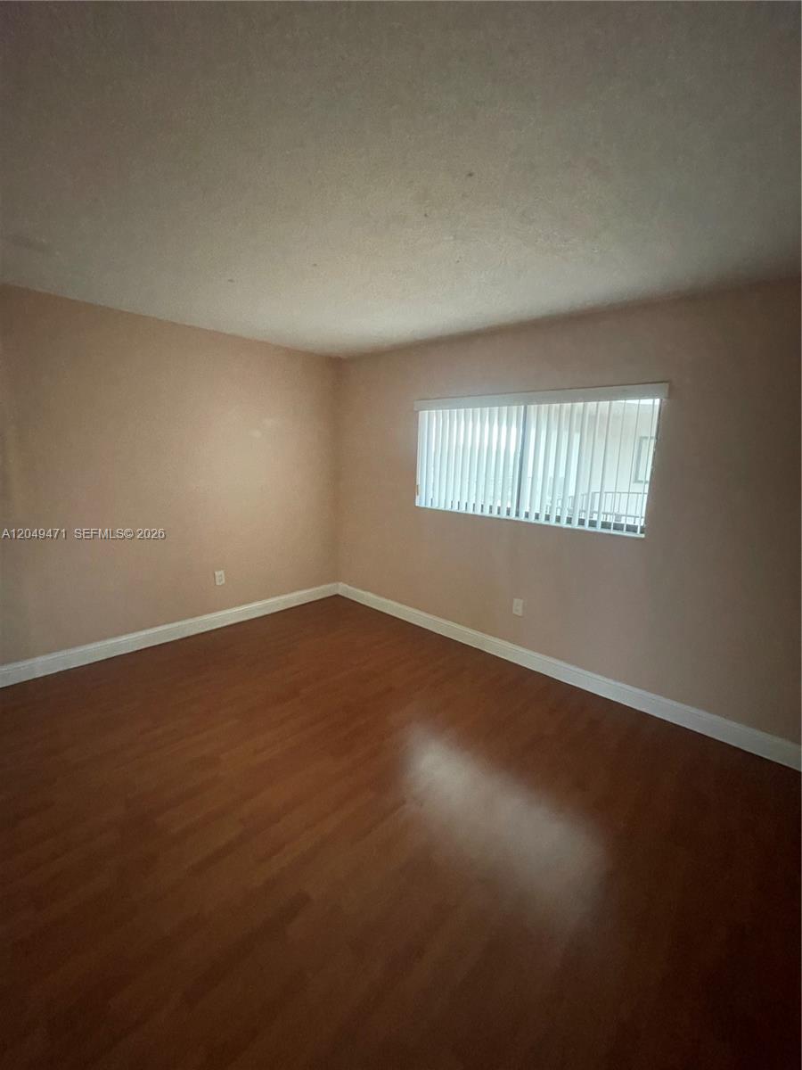An empty room features light-colored walls, wood-look flooring, and a window with vertical blinds — 8400 SW 133rd Ave Rd # 424, Miami FL 33183, MIAMI, FL