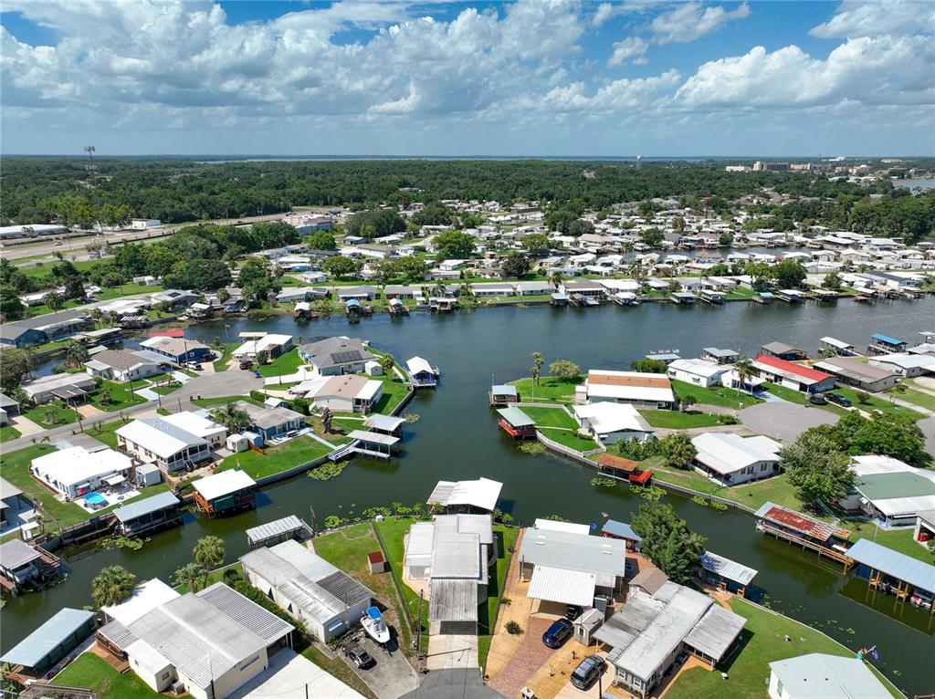 An aerial view shows a residential community with mobile homes situated along a narrow canal — 30041 WAUSAUKEE DRIVE, TAVARES, FL