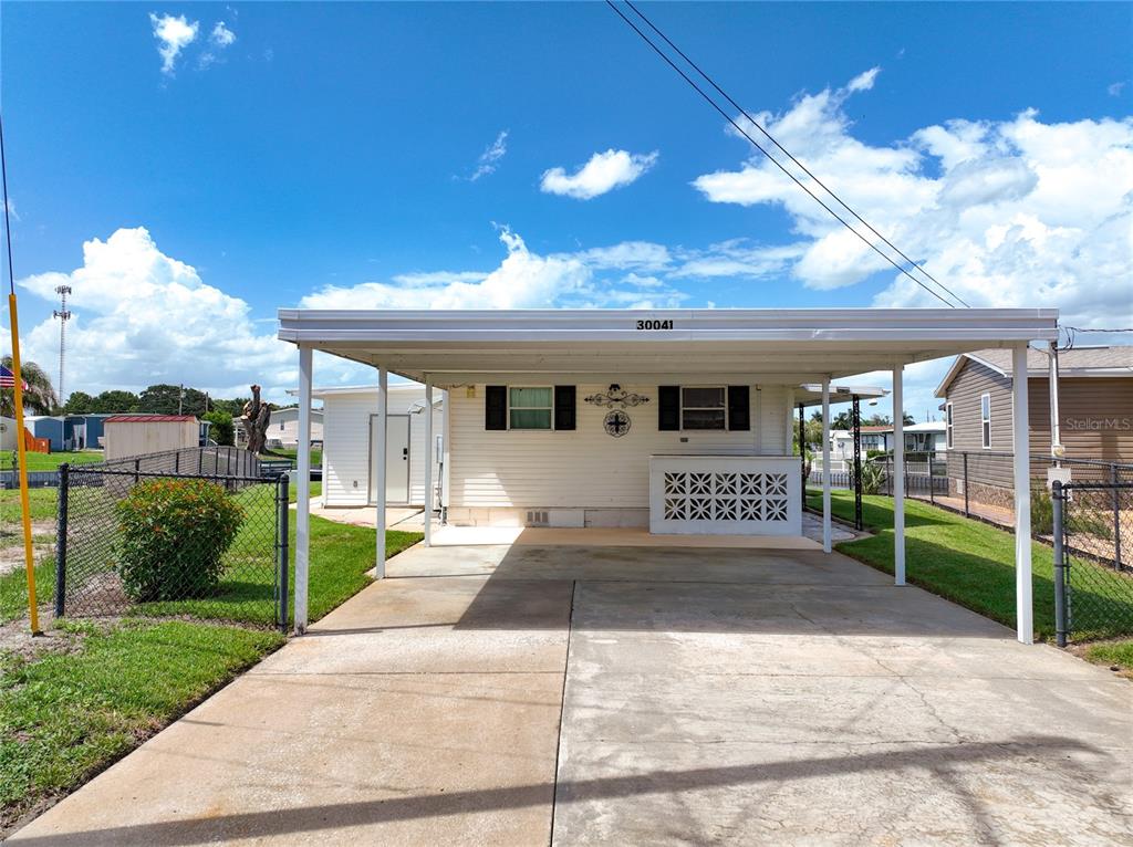 A white mobile home features a large attached carport and a concrete driveway — 30041 WAUSAUKEE DRIVE, TAVARES, FL
