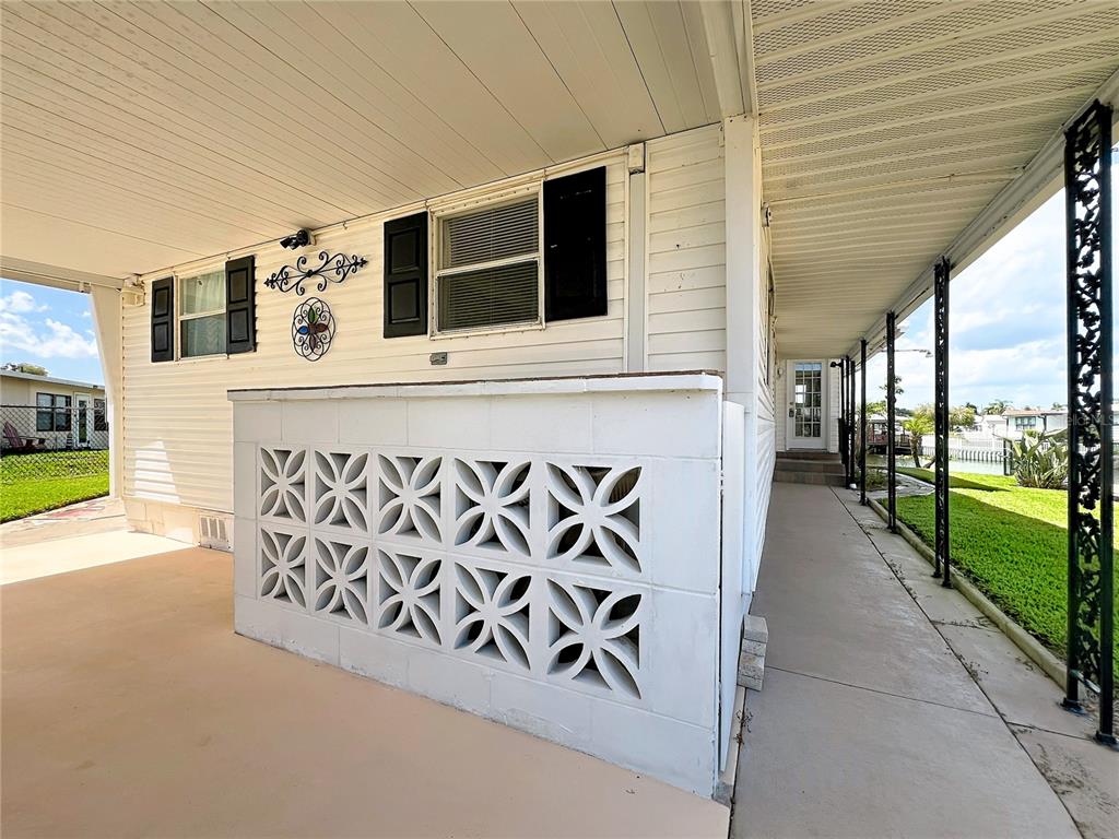 A covered patio features a decorative concrete block wall and a walkway along the exterior — 30041 WAUSAUKEE DRIVE, TAVARES, FL