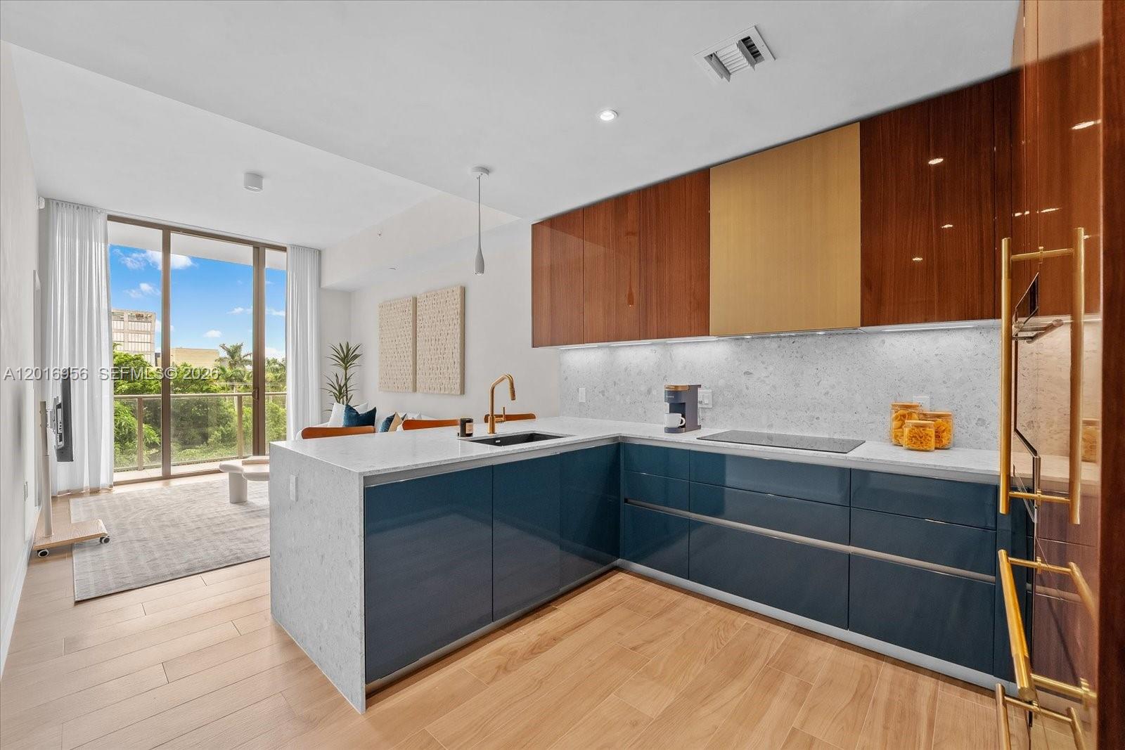 A modern kitchen features blue lower cabinets, wood-toned upper cabinets, and a white stone countertop — 2678 Tigertail Ave # 315, Miami FL 33133, MIAMI, FL