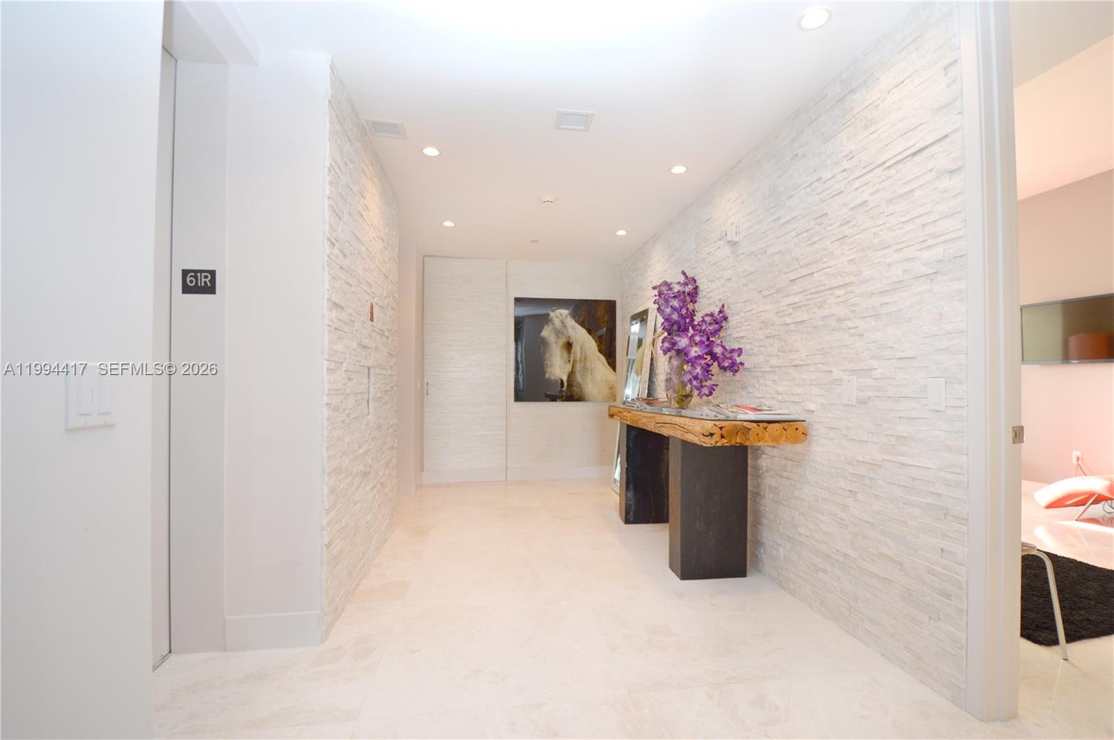 A hallway features white stone-textured walls, a live-edge console table, and a horse portrait — 1100 Biscayne Blvd # 6104, Miami FL 33132, MIAMI, FL