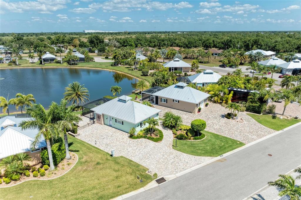 An aerial view shows two adjacent houses with metal roofs near a small lake — 8153 SW BIMINI WAY LOT 30, ARCADIA, FL