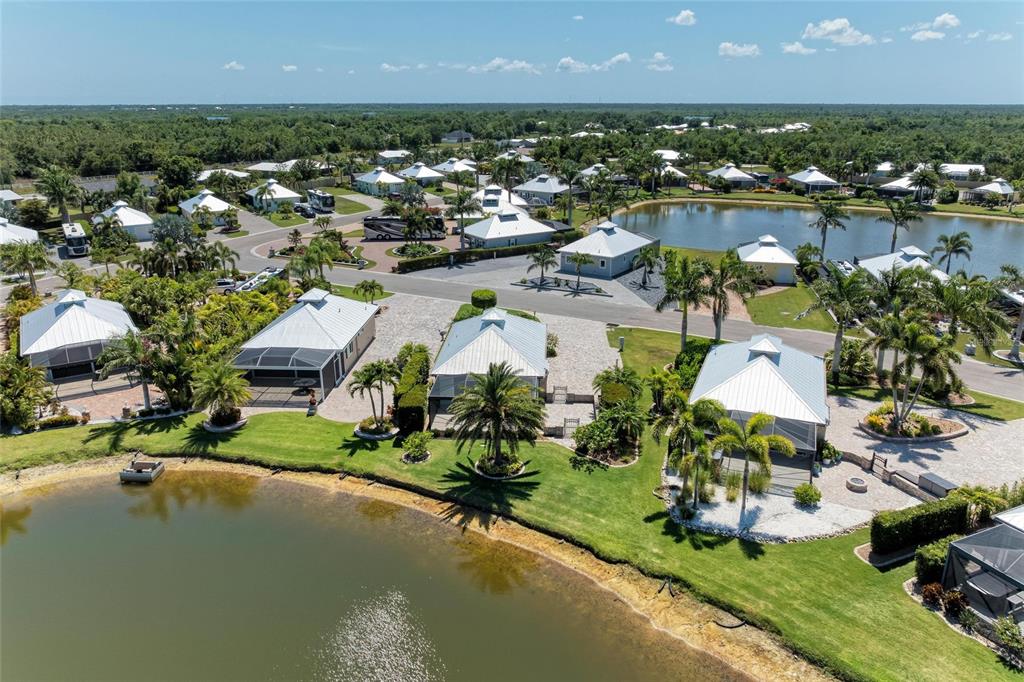 An aerial view shows several houses with metal roofs situated along a small lake — 8153 SW BIMINI WAY LOT 30, ARCADIA, FL