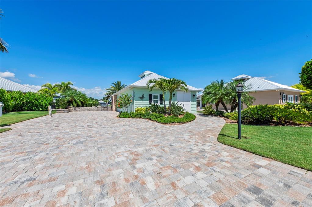 A light green house with a paver driveway and palm trees under a blue sky — 8153 SW BIMINI WAY LOT 30, ARCADIA, FL
