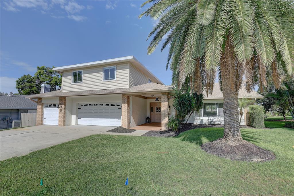 A two-story house with a beige exterior, a two-car garage, and a large palm tree — 7600 DREW OAK DRIVE, SEMINOLE, FL