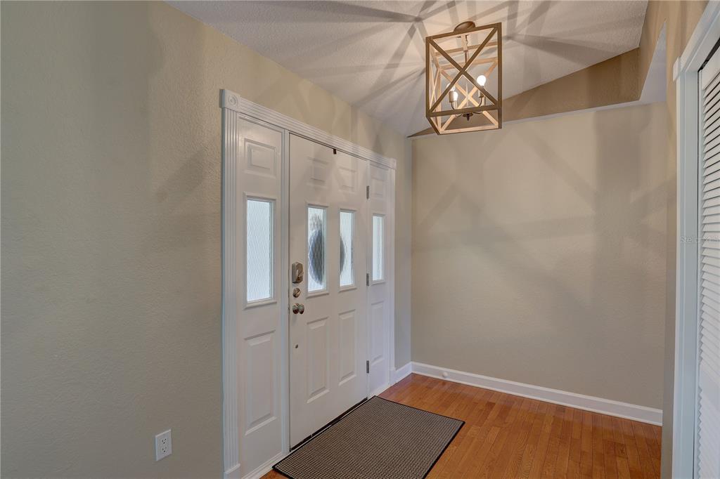 An entryway features a white front door, hardwood flooring, and a geometric wood-framed light fixture — 7600 DREW OAK DRIVE, SEMINOLE, FL