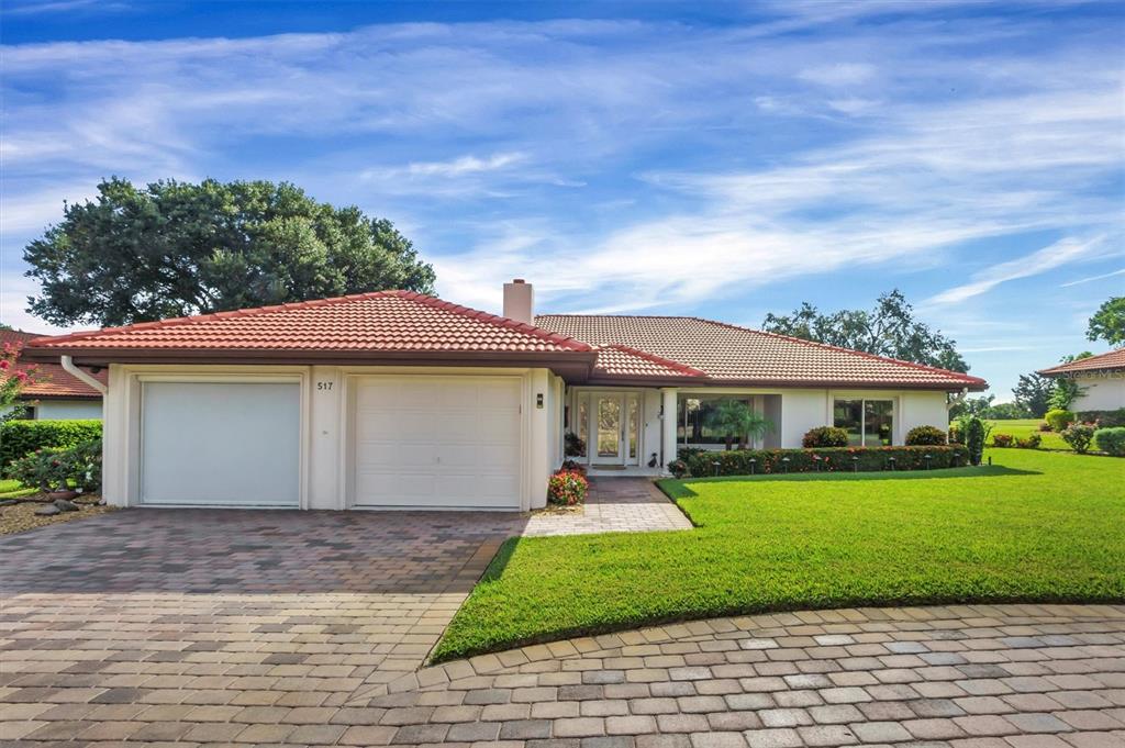 A single-story house with a tiled roof, two-car garage, and a paved driveway — 517 CLUBHOUSE DRIVE, LAKE WALES, FL