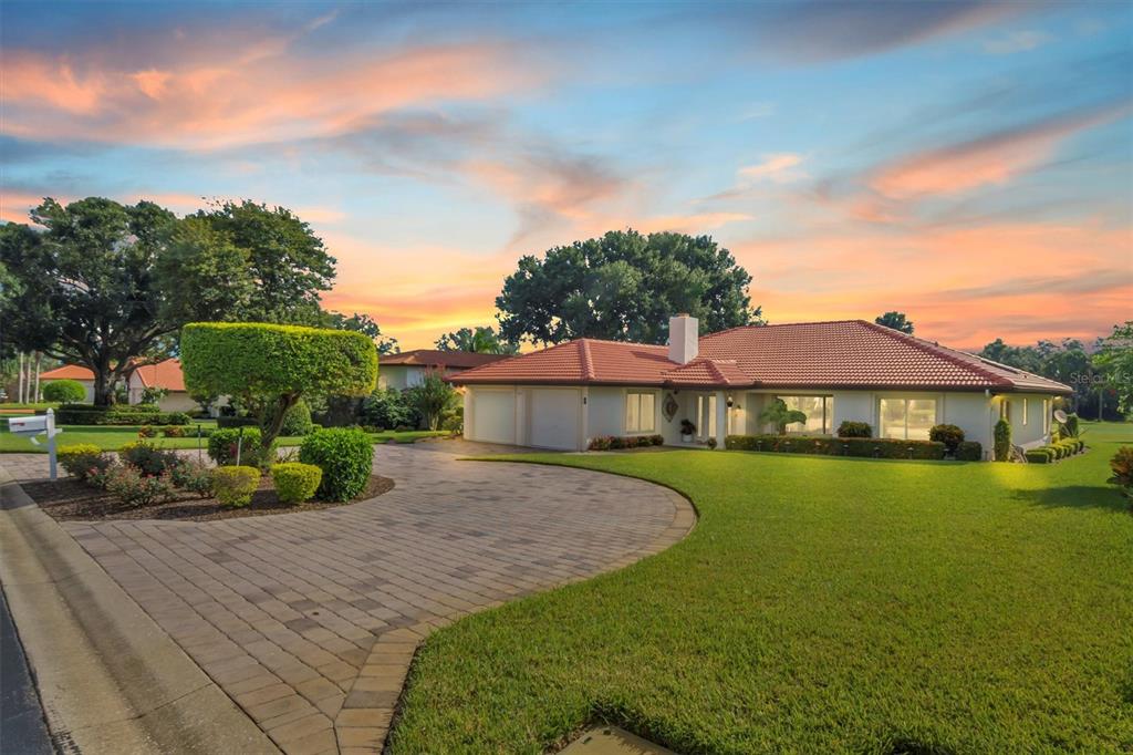 A single-story house with a red tile roof and a paved driveway at sunset — 517 CLUBHOUSE DRIVE, LAKE WALES, FL