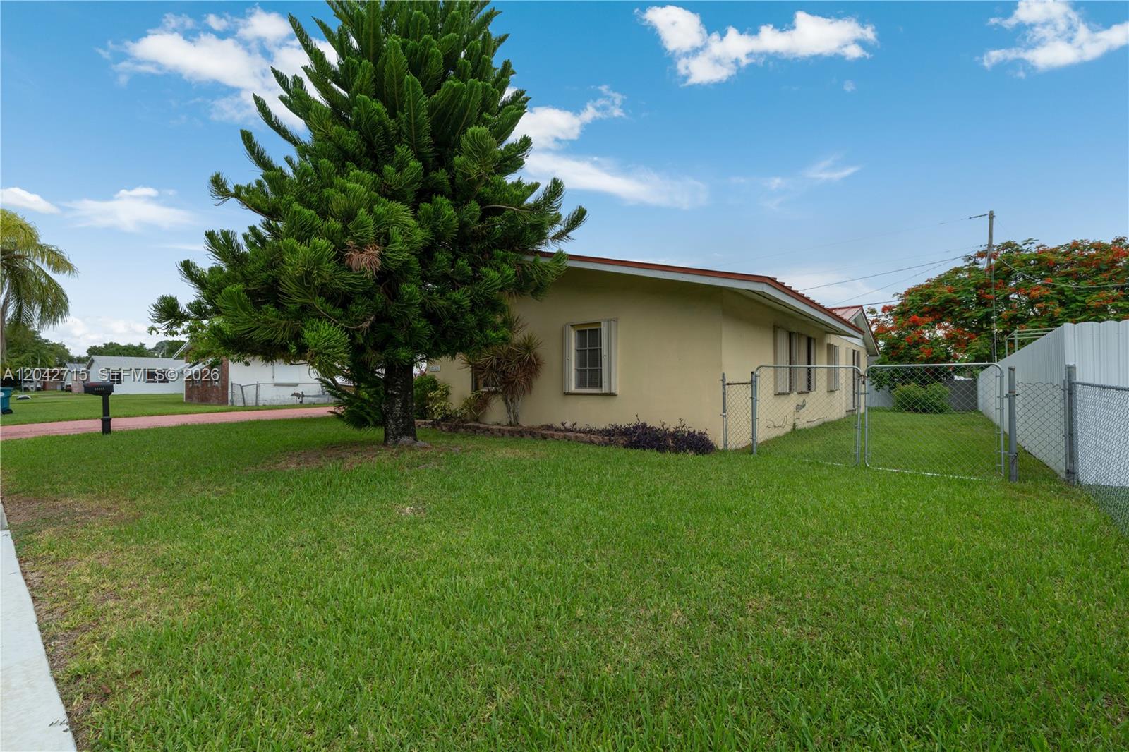 A single-story house with a tan exterior sits on a grassy lot with a tree — 10315 SW 200th St, Cutler Bay FL 33157, CUTLER BAY, FL