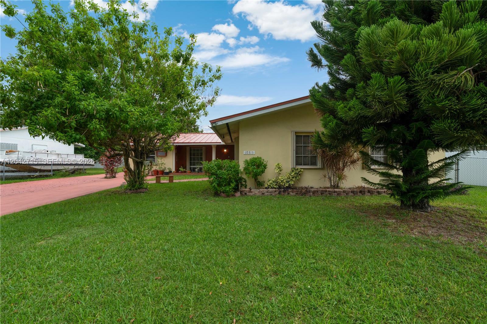 A single-story house with a yellow exterior, a red metal roof, and a front lawn — 10315 SW 200th St, Cutler Bay FL 33157, CUTLER BAY, FL