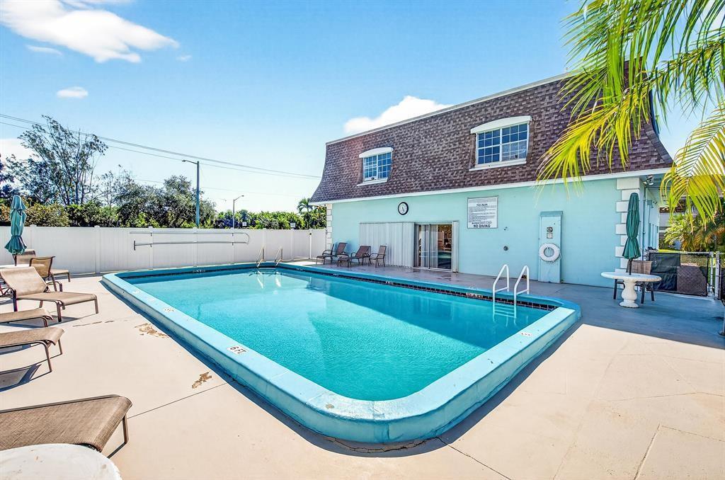 A rectangular swimming pool sits on a patio in front of a two-story building — 1901 Indian River Boulevard # 104C, Vero Beach FL 32960, VERO BEACH, FL