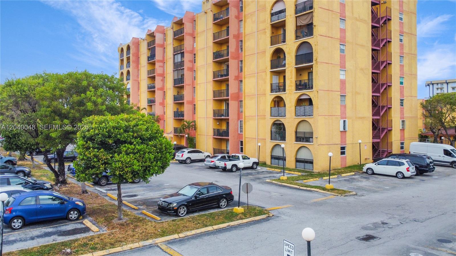 An exterior view of a multi-story yellow apartment building with balconies and a parking lot — 4717 NW 7th St # 10, Miami FL 33126, MIAMI, FL