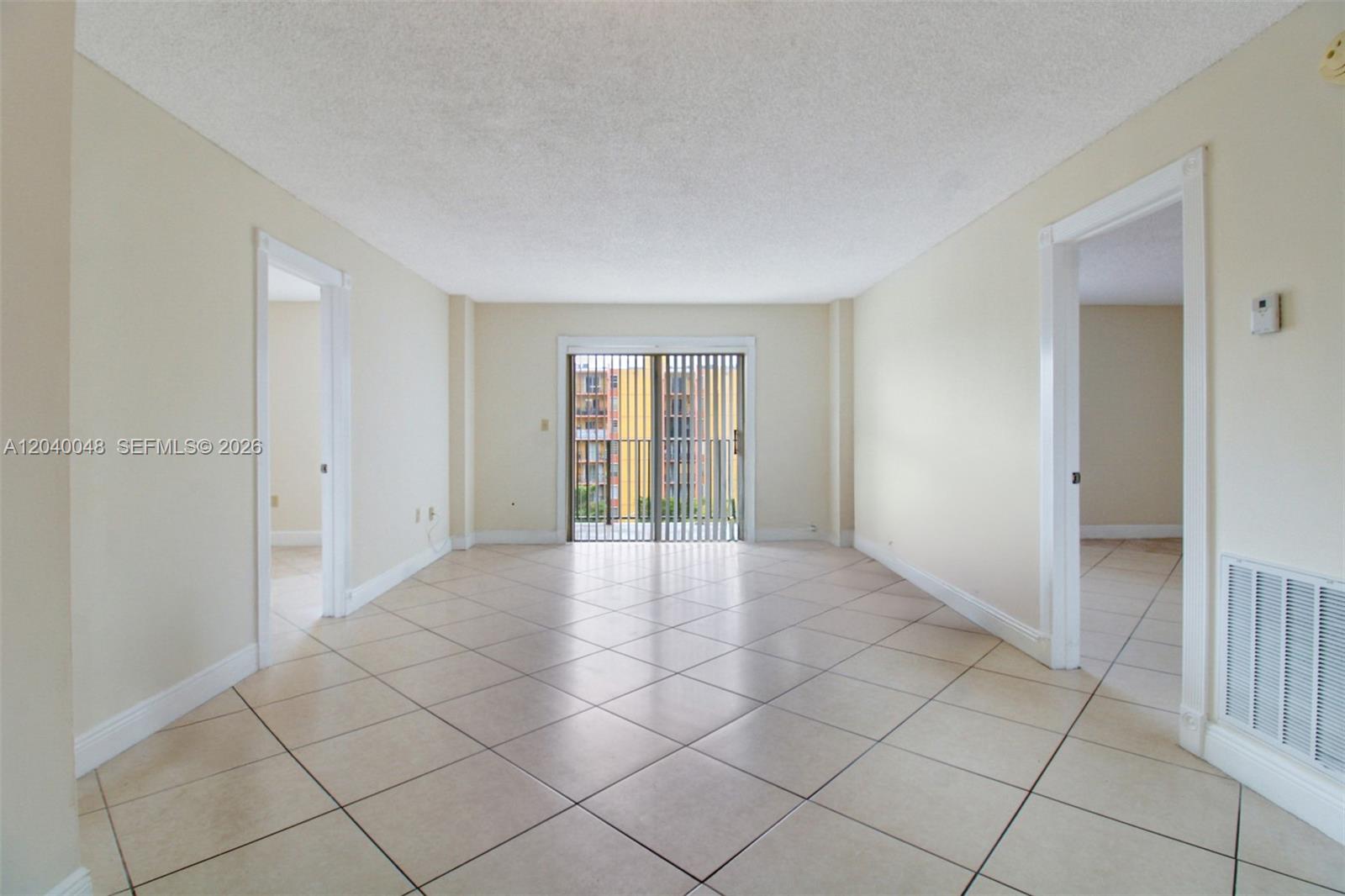 An empty room with beige tile flooring, white walls, and a sliding glass balcony door — 4717 NW 7th St # 10, Miami FL 33126, MIAMI, FL