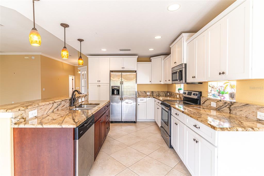 A kitchen features white cabinets, granite countertops, stainless steel appliances, and a dark wood island — 3715 SEBRING PARKWAY, SEBRING, FL