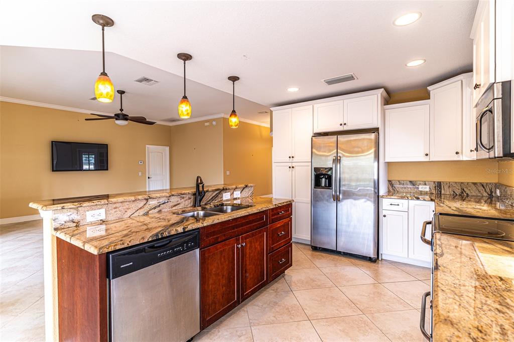 A kitchen features a granite-topped island, stainless steel appliances, and white cabinetry — 3715 SEBRING PARKWAY, SEBRING, FL