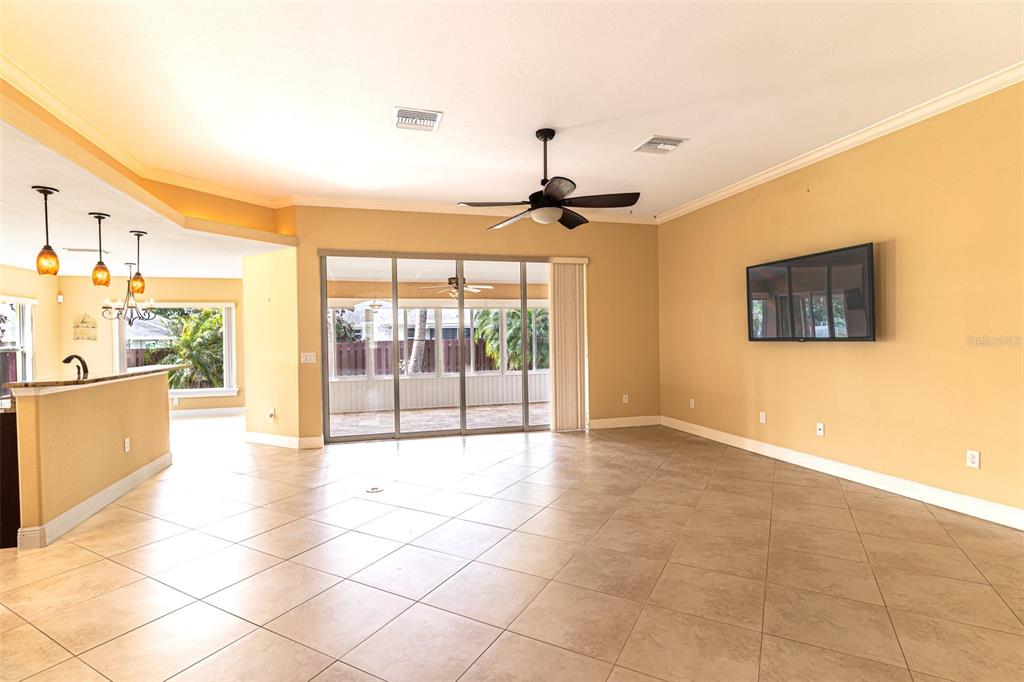 A living room with beige walls, tile flooring, a ceiling fan, and sliding glass doors — 3715 SEBRING PARKWAY, SEBRING, FL