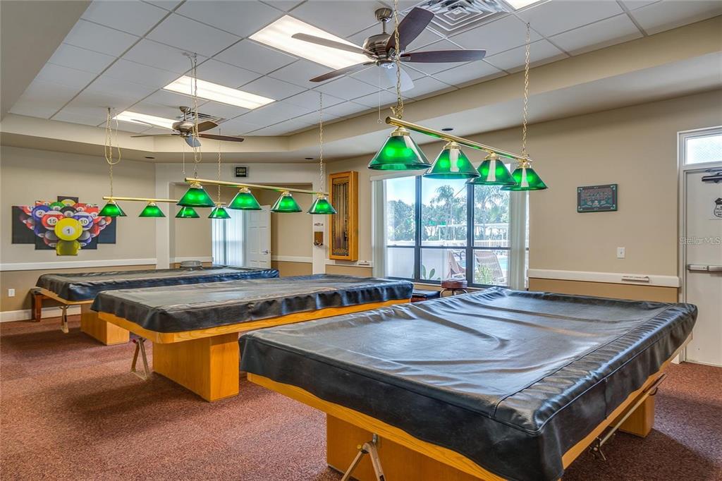 A billiards room features three pool tables with black covers under green pendant lights — 5926 CORMORANT COURT, LAKELAND, FL