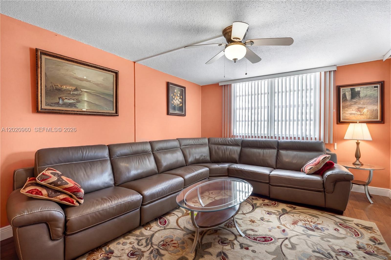 A living room features a large brown leather sectional, a glass coffee table, and peach walls — 1849 S Ocean Dr # 305, Hallandale Beach FL 33009, HALLANDALE BEACH, FL