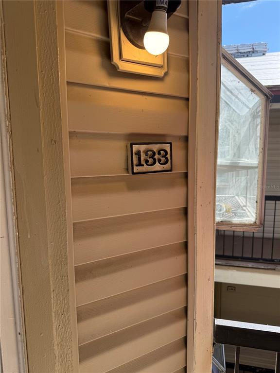 A close-up view of a beige vinyl-sided wall featuring a house number 133 plaque — 1948 LAKE ATRIUMS CIRCLE UNIT 133, ORLANDO, FL