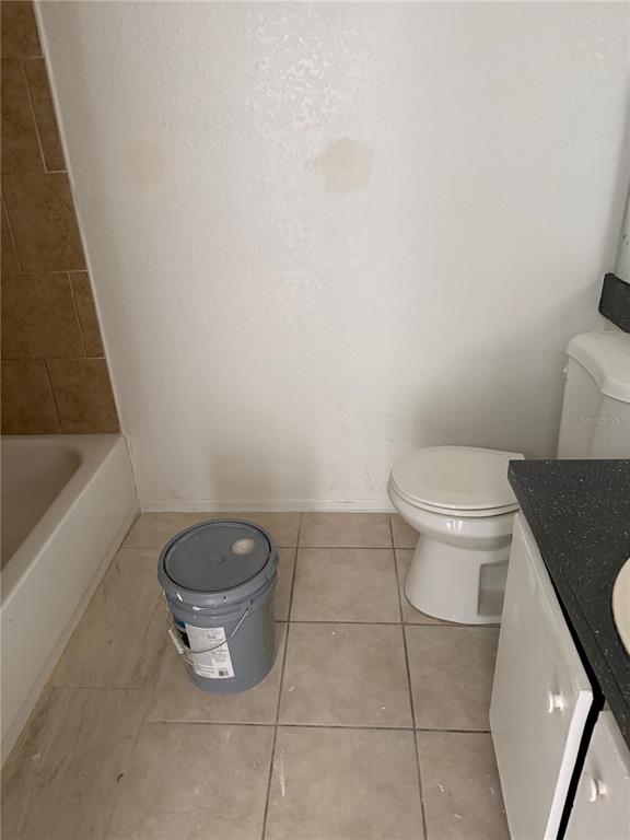 A bathroom features a toilet, a vanity, a bathtub, and a paint bucket on tile floors — 1948 LAKE ATRIUMS CIRCLE UNIT 133, ORLANDO, FL