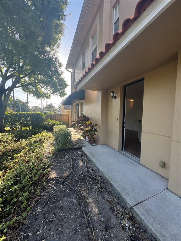 A concrete walkway leads to an open doorway along the side of a tan building — 3210 W HORATIO STREET UNIT 1, TAMPA, FL