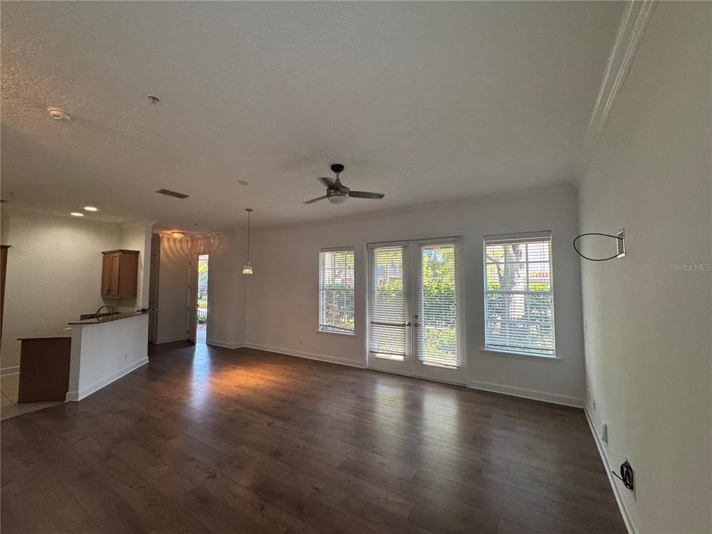 An open-concept living area features dark wood flooring, a ceiling fan, and glass patio doors — 3210 W HORATIO STREET UNIT 1, TAMPA, FL