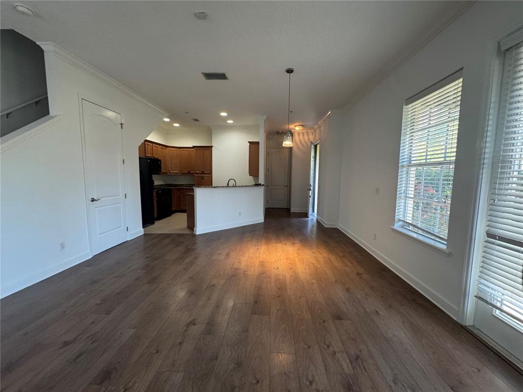 An open-concept living area features wood-look flooring, a kitchen with dark cabinets, and large windows — 3210 W HORATIO STREET UNIT 1, TAMPA, FL