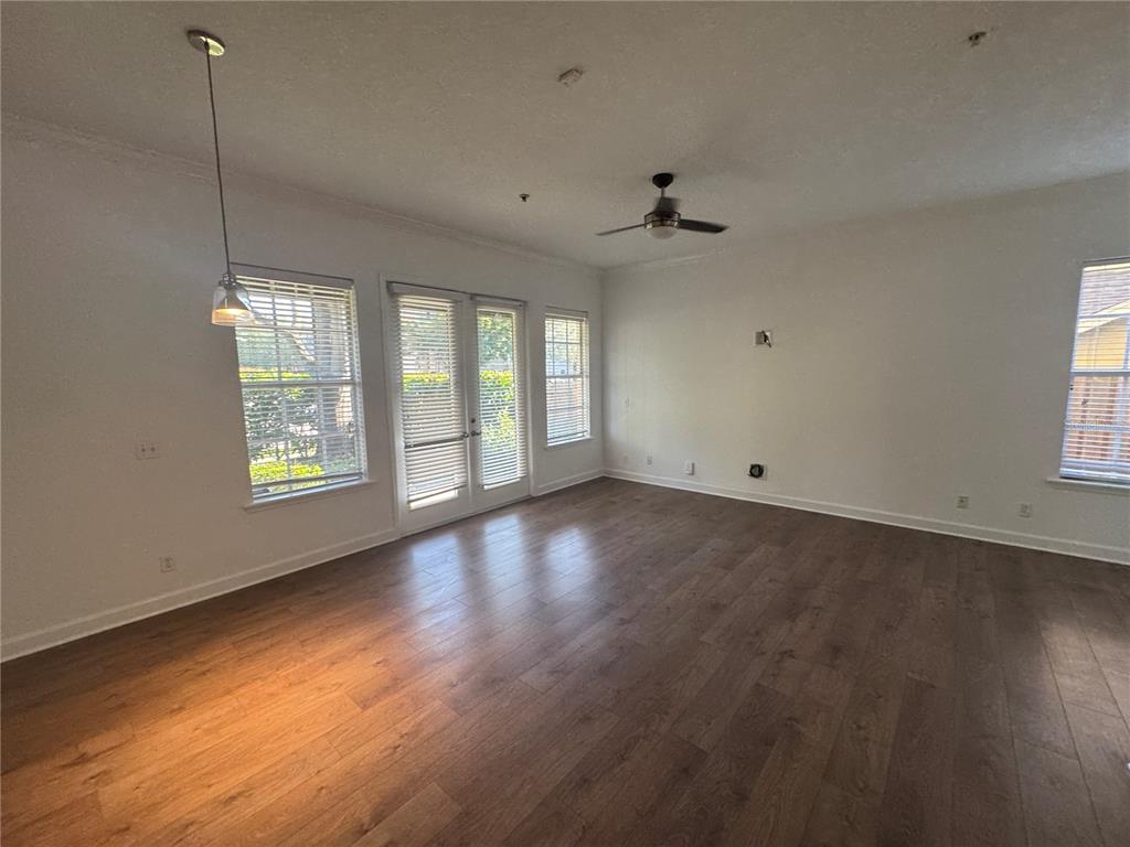 An empty living room features wood-look flooring, a ceiling fan, and glass doors to outside — 3210 W HORATIO STREET UNIT 1, TAMPA, FL