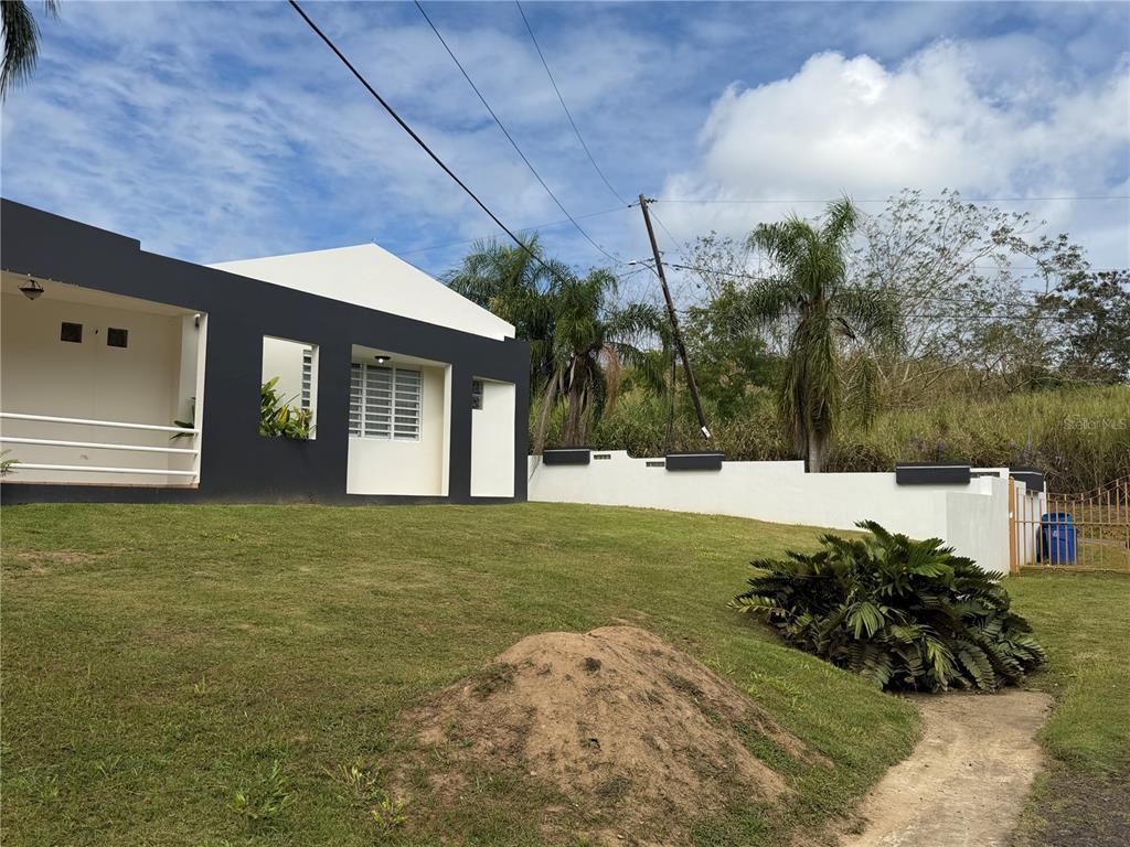 A modern house with a black and white exterior sits on a grassy sloped lot — 16 TRINITARIA, GURABO, PR