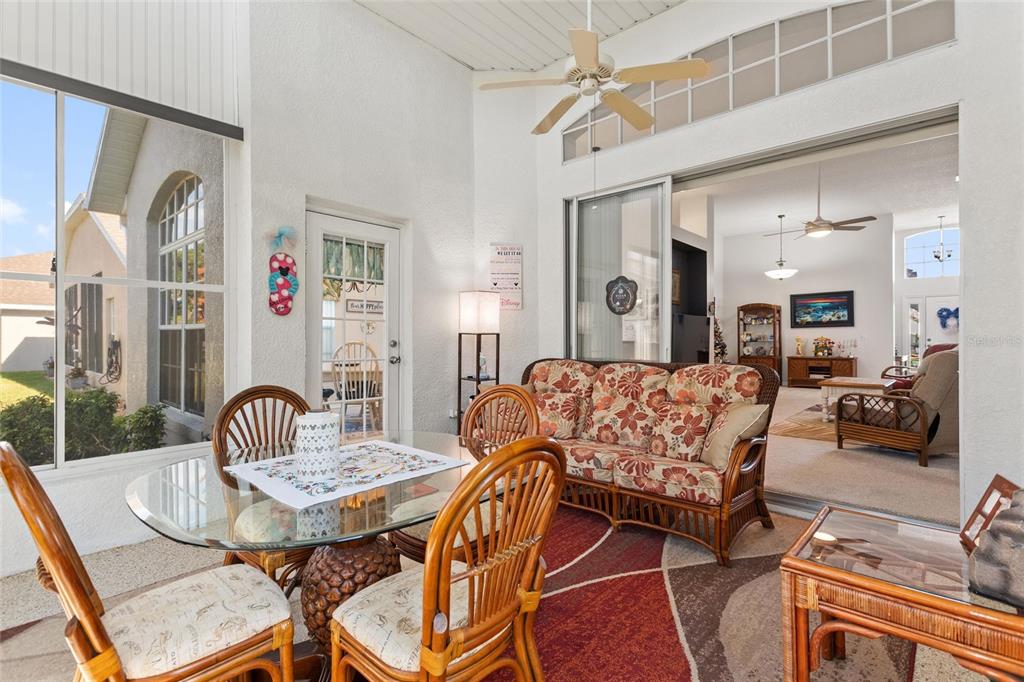 A sunroom features a glass-topped dining table, wicker furniture, and a sliding door to the interior — 215 FITZGERALD LN, DAVENPORT, FL