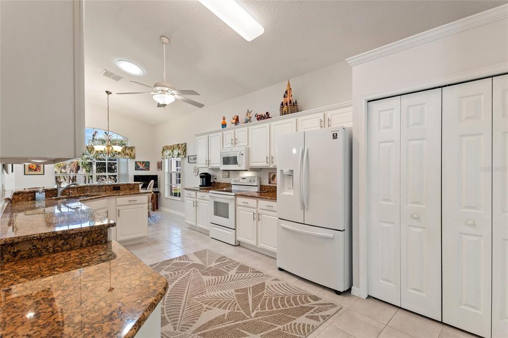 A kitchen features white cabinets, granite countertops, a white refrigerator, and a patterned area rug — 215 FITZGERALD LN, DAVENPORT, FL
