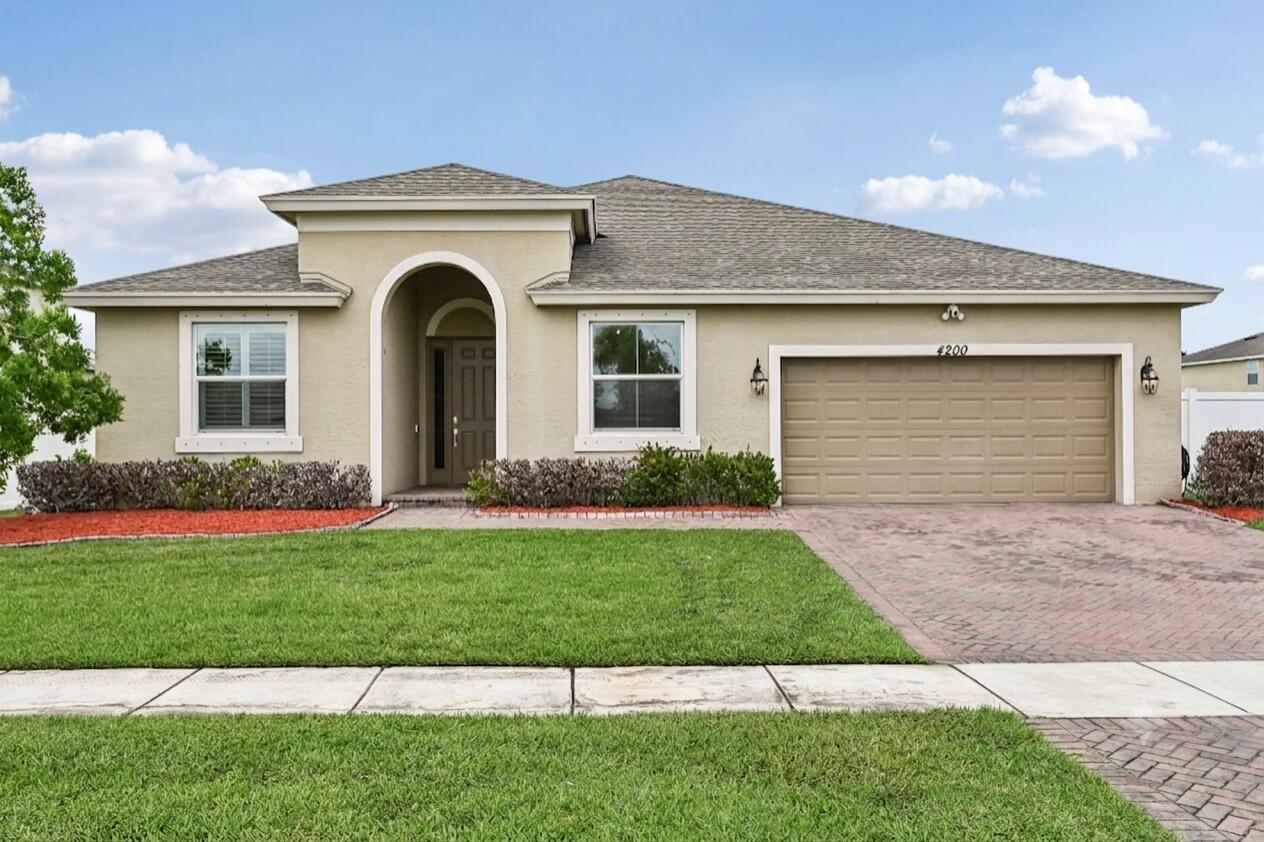 A single-story tan house with a two-car garage, arched entryway, and a paved driveway — 4200 Birkdale Drive, Fort Pierce FL 34947, FORT PIERCE, FL