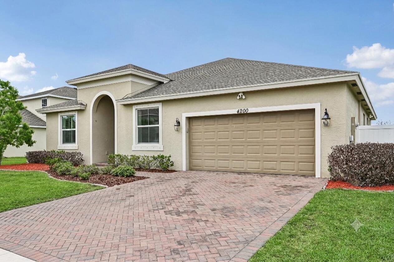 A single-story house with a tan stucco exterior, a two-car garage, and a brick driveway — 4200 Birkdale Drive, Fort Pierce FL 34947, FORT PIERCE, FL