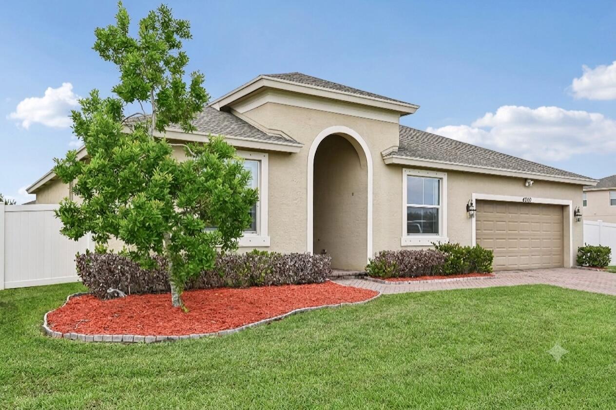 A single-story tan stucco house with an arched entryway, a two-car garage, and landscaping — 4200 Birkdale Drive, Fort Pierce FL 34947, FORT PIERCE, FL