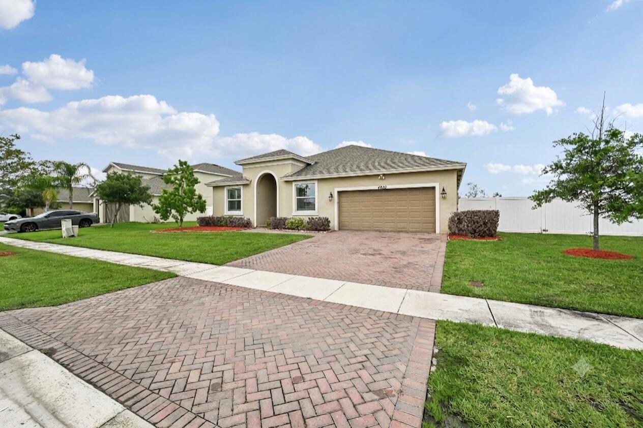 A single-story suburban house with a brick paver driveway, tan stucco exterior, and two-car garage — 4200 Birkdale Drive, Fort Pierce FL 34947, FORT PIERCE, FL