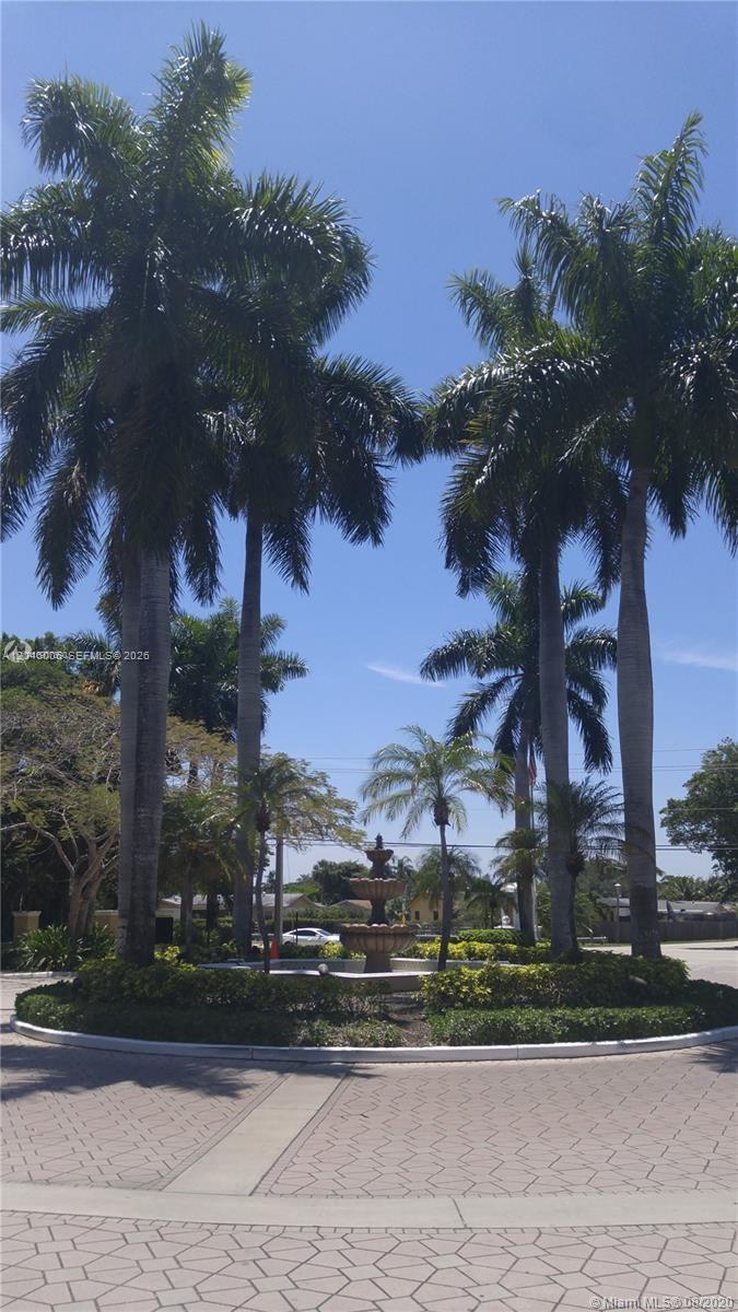 A tiered fountain sits in the center of a circular driveway surrounded by palm trees — 4015 W Mcnab Rd # D210, Pompano Beach FL 33069, POMPANO BEACH, FL