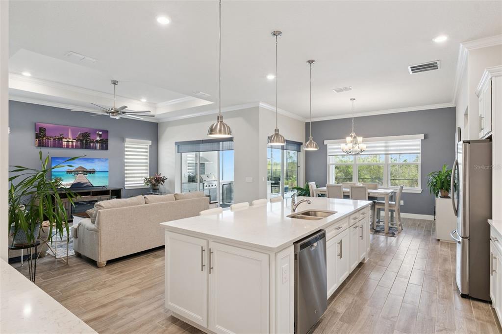 A modern open-concept kitchen with a white island overlooks a living room and dining area — 2745 NATURE VIEW ROAD, ST CLOUD, FL