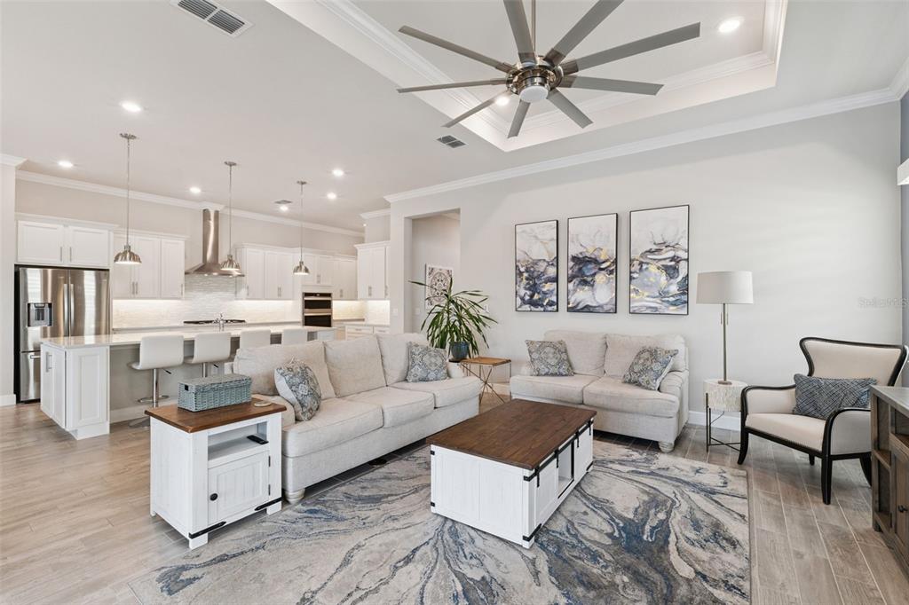 A bright, open-concept living room and kitchen featuring white cabinetry, neutral furniture, and tile flooring — 2745 NATURE VIEW ROAD, ST CLOUD, FL