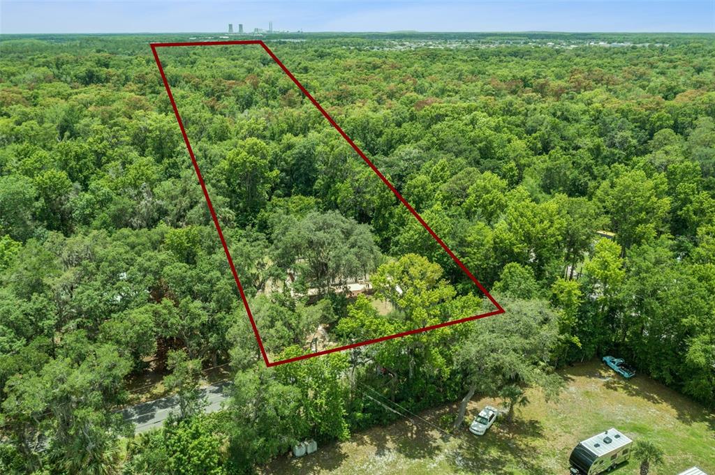 An aerial view shows a wooded lot outlined in red with a house nestled inside — 16250 HAMILTON DR, ORLANDO, FL