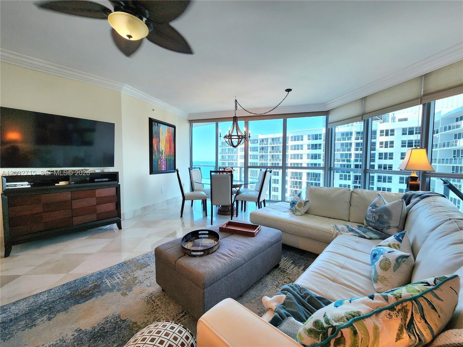 A living and dining area features floor-to-ceiling windows, a sectional sofa, and tile flooring — 3101 S Ocean Dr # 1106, Hollywood FL 33019, HOLLYWOOD, FL