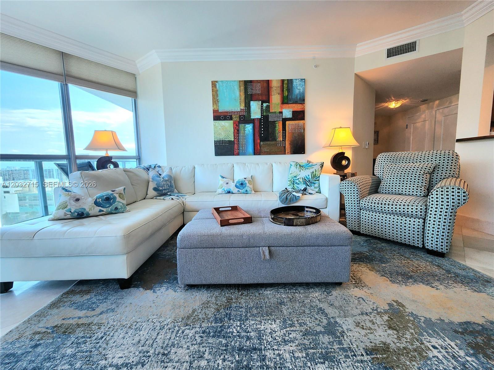 A living room features a white sectional sofa, a gray ottoman, and a patterned armchair — 3101 S Ocean Dr # 1106, Hollywood FL 33019, HOLLYWOOD, FL