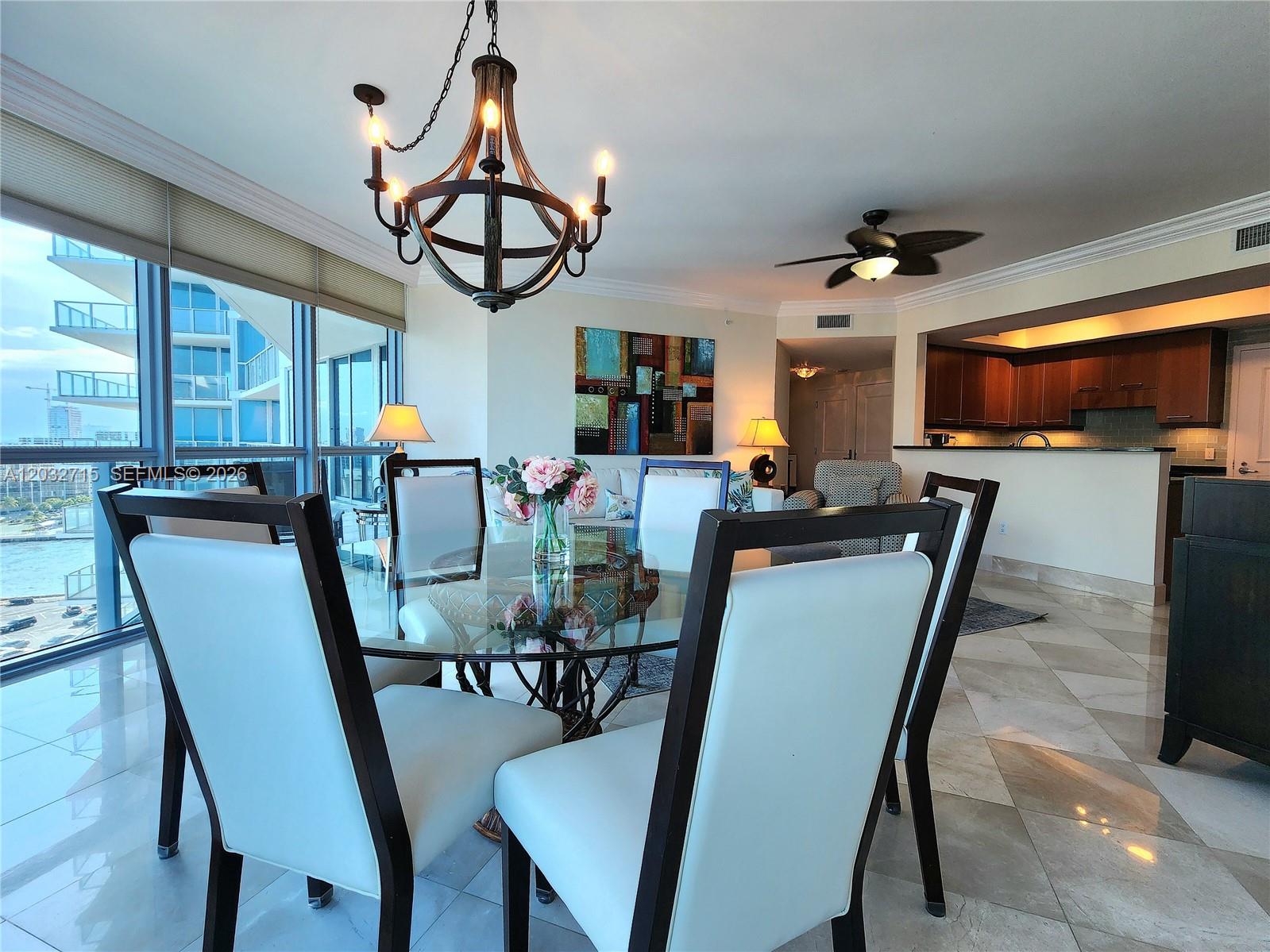 A dining area with a glass table and chandelier overlooks a balcony and kitchen — 3101 S Ocean Dr # 1106, Hollywood FL 33019, HOLLYWOOD, FL