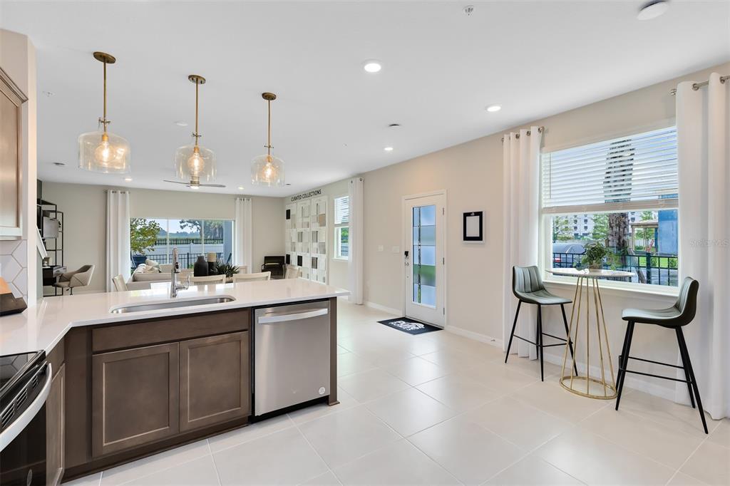 A modern kitchen with dark wood cabinets, white countertops, and a dining area by windows — 3242 PONDSIDE WAY, SANFORD, FL