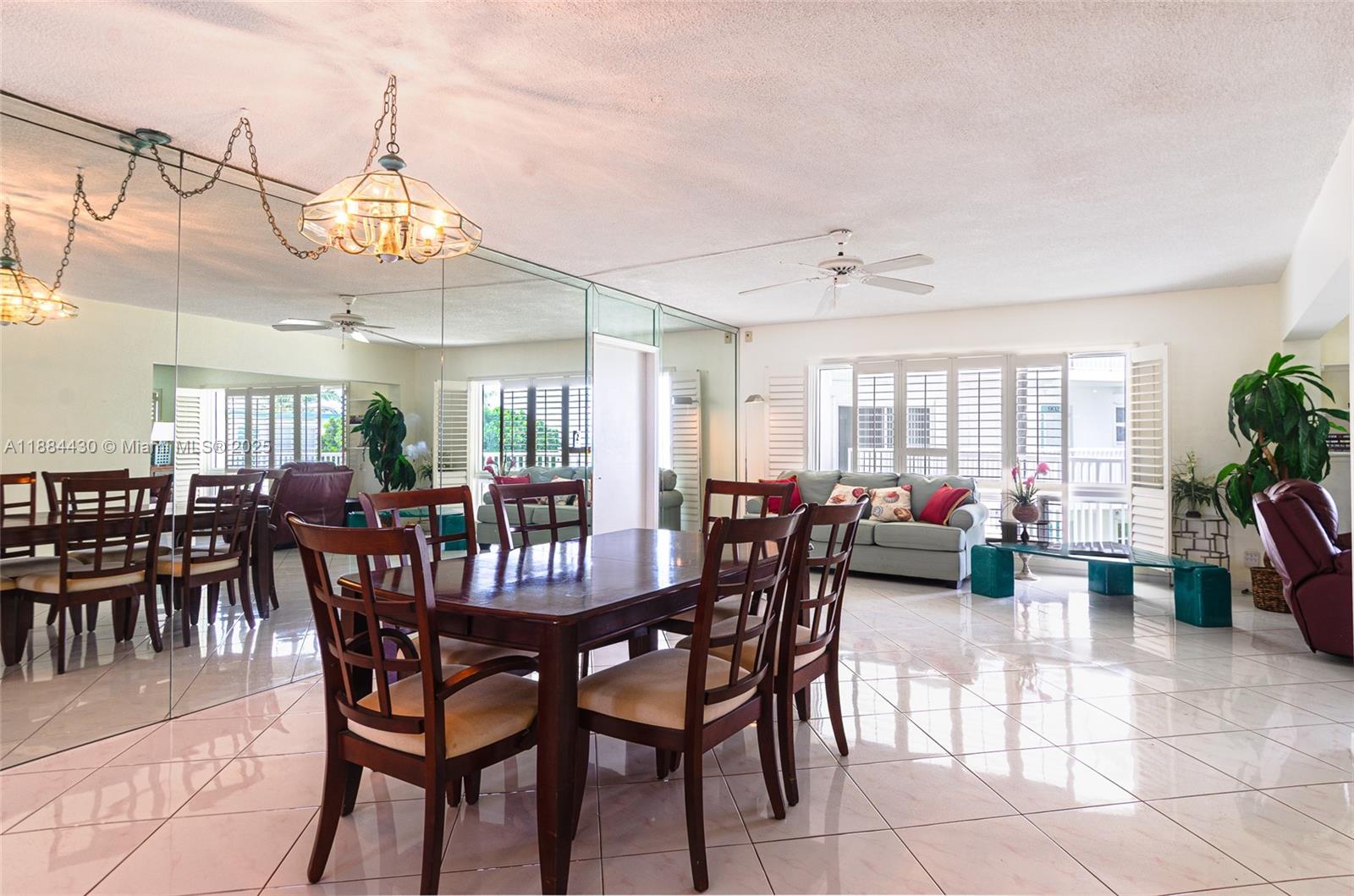 A dining and living area features tiled floors, mirrored walls, and a ceiling fan — 1470 S Ocean Blvd # 702, Pompano Beach FL 33062, POMPANO BEACH, FL